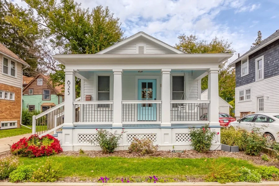 White house exterior with a covered porch, columns and flowers
